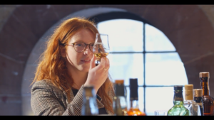 Girl with Glencairn glass at bar looking at whisky