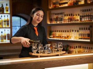 Waitress pouring drams at the Amber Bar with a whisky stave
