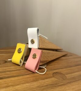 Three wooden door stops with coloured fabric stacked on top of each other on a wooden table.