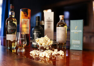 Global Movie Day, 3 bottles of whisky with their boxes, a quaich full of popcorn and a dram of whisky in a glass.