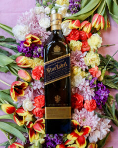 Bottle of Johnnie Walker Blue Label for March Whiskies of the Month with colourful flowers in the background
