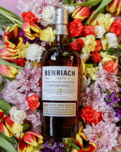Bottle of Benriach 25yo for March Whiskies of the Month with colourful flowers in the background
