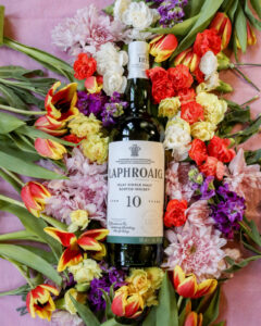 Bottle of Laphroaig 10yo for March Whiskies of the Month with colourful flowers in the background