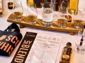 Blend your own whisky experience at The Scotch Whisky Experience. Pictured, certificate, whisky bag, small blend bottle of whisky, glass, whisky stave with whisky glasses.