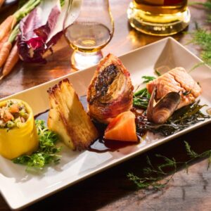 Food dish with glass of whisky and bottle in background.