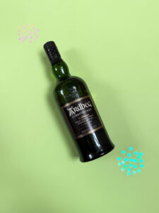 Bottle of Scotch whisky against green background with glitter gems.