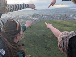Image of Edinburgh from Arthur's Seat with 4 people pointing in the direction of The Scotch Whisky Experience.