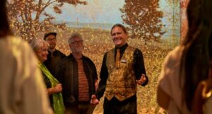 Tour guide and visitors at The Scotch Whisky Experience against a projection of barley fields.