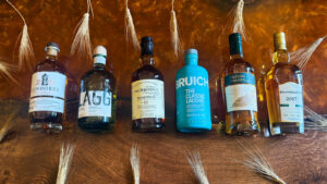 Bottles of Scotch whisky on an amber table with barley