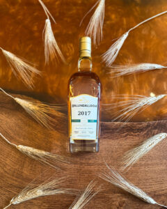 Bottle of Ballindalloch Scotch Whisky on an Amber coloured table with barley.