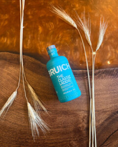 Bottle of Bruichladdich Scotch Whisky on an Amber coloured table with barley.