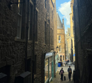 Image of Fleshmarket Close looking down onto building with a turret on Cockburn Street and two people in the background walking down.
