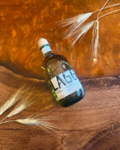 Bottle of Lagg Scotch Whisky on an Amber coloured table with barley.