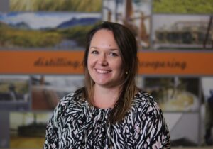 Headshot of female in front of whisky and distillery images.
