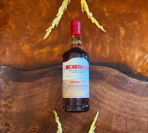 Bottle of Benromach Organic Scotch whisky on an amber table with barley.