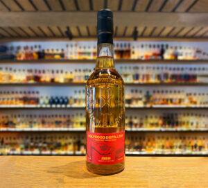 Bottle of Holyrood Distillery Ambir Scotch whisky placed on a bar with whisky bottles in the background.
