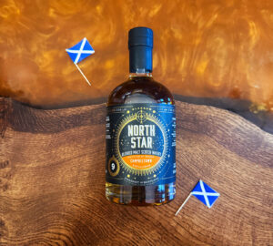 Bottle of North Star Campbeltown Scotch whisky on an amber table with Scottish flags.