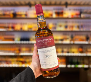 Bottle of Woodrow's of Edinburgh 30 year old Scotch whisky held up against a whisky bar.