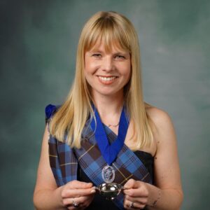 Headshot of female wearing tartan holding a medal.